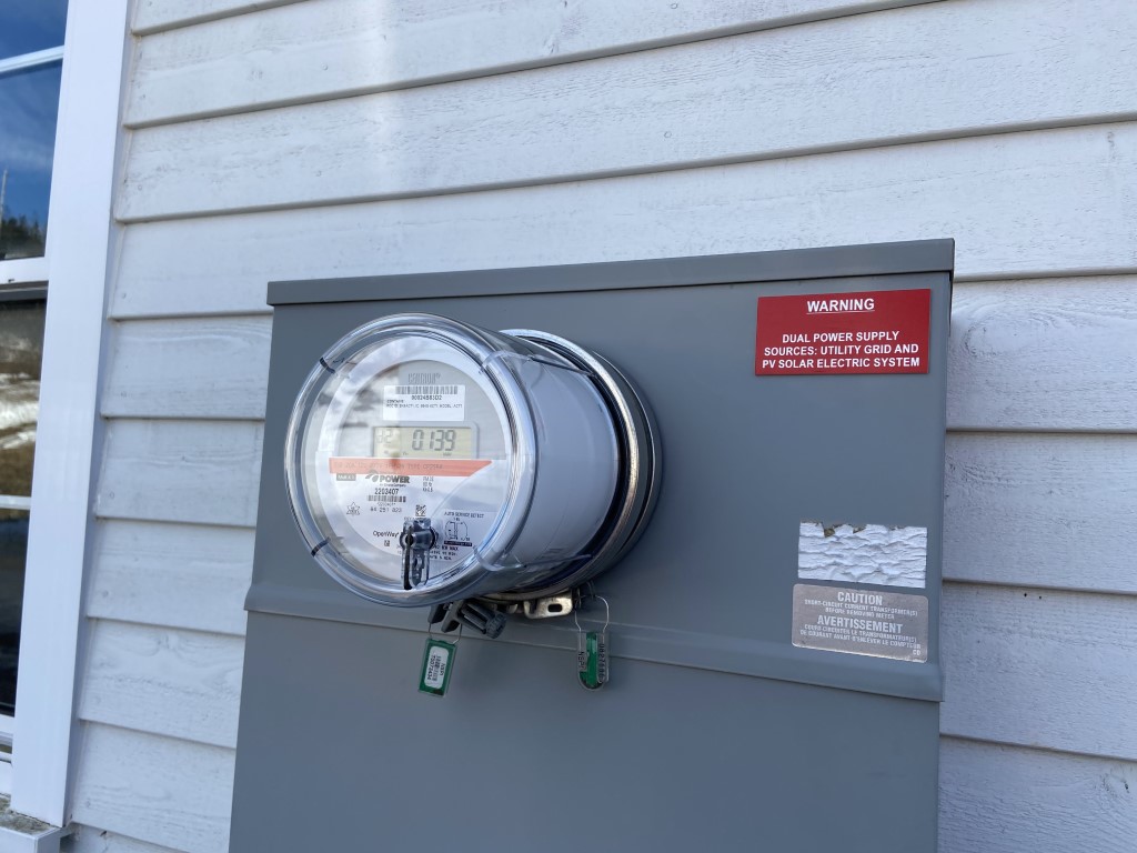 New smart meter installed on a meter base with solar dual-supply warning label